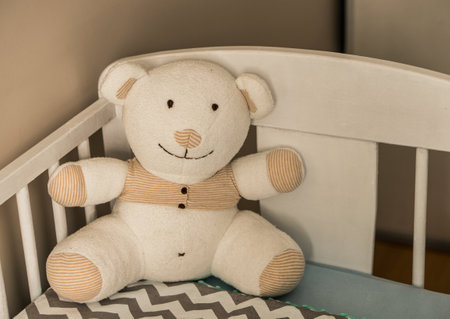 A closeup shot of a teddy bear on a baby bed