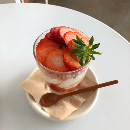 A vertical shot of a strawberry smoothie with a spoon and a saucerの写真素材