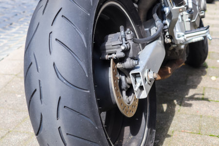 A closeup of a cool modern racing motorcycle rear wheel parked outdoors