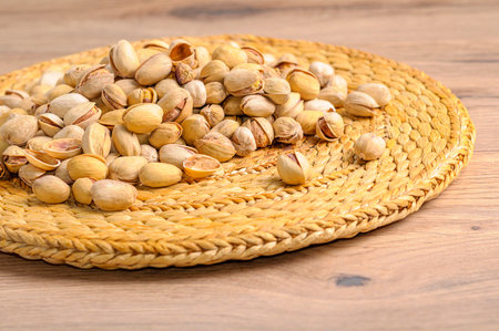 A heap of roasted pistachios on a round jute rug