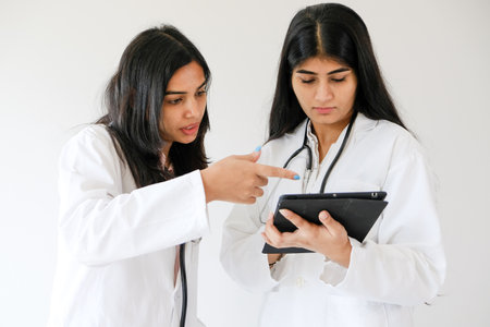 Two female South Asian doctors checking the tabletの写真素材