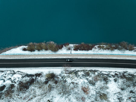 A top view shot of a road near a lake in winterの写真素材