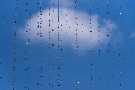 A selective focus of water dripping from a roof against blue skyの写真素材