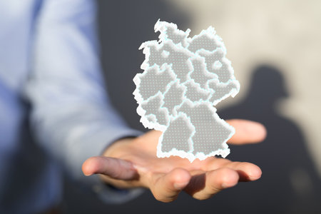 A 3d modeling of the German map concept over a human hand in front of a background with a human shadowの写真素材