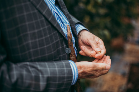 A selective focus shot of an old male hands and body detail outdoors under sunlightの写真素材