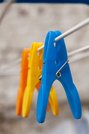 A closeup of blue, yellow, and orange clothespins on a wire