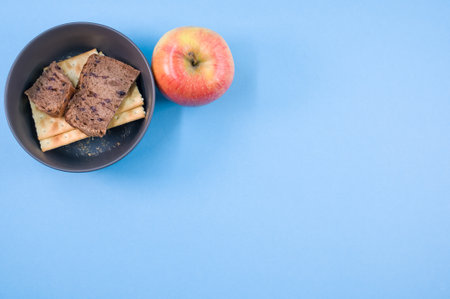 A closeup of tasty crackers with slices of brown bread in the bowl on the blue  surfaceの写真素材