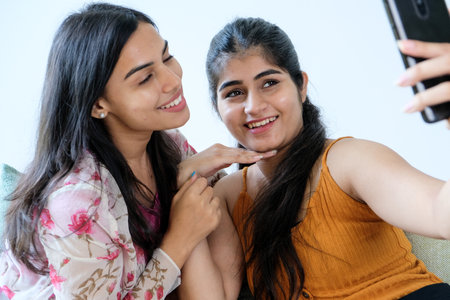 Two Indian best friends happily taking a selfie at homeの写真素材