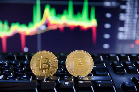 A closeup shot of Bitcoins on the keyboard and graphs on the screen - the concept of trading