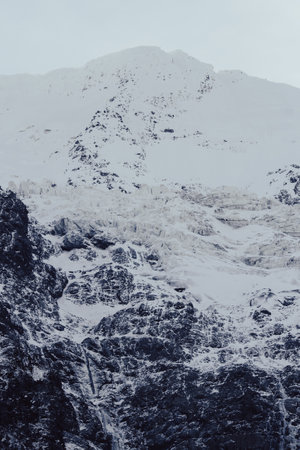 A vertical shot of rocky mountains covered in the now - perfect for wallpapers