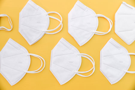A closeup shot of white face masks isolated on a yellow surface
