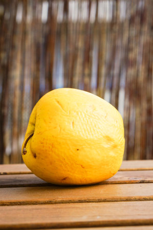 A vertical shot of a yellow apple on a wooden tableの写真素材