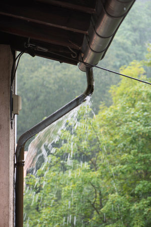 A vertical closeup of a house downpipe during rain.