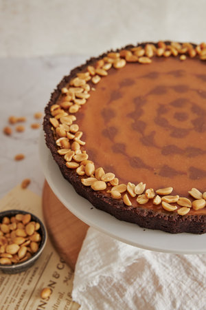 A vertical shot of a delicious and nicely decorated peanut butter cheesecake on a stand