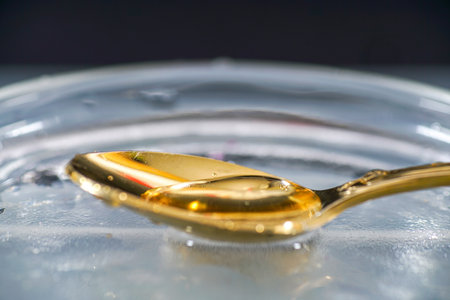 A selective focus shot of golden spoon with waterの写真素材