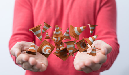 A 3d rendering of orange and white striped traffic road cones in handsの写真素材