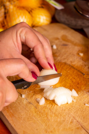 A closeup of a woman slicing onion on a cutting boardの写真素材
