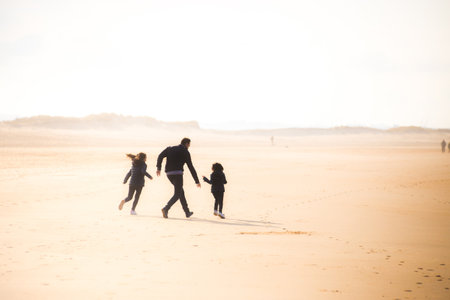 A man running and having fun with his daughters in the desertの写真素材