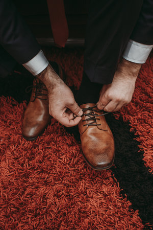 The groom tying his wedding brown shoesの写真素材