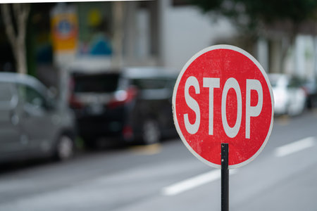 A closeup of a red stop sign on the road with blurred backgroundの写真素材