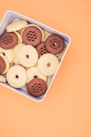 A vertical shot of cookies in a box on an orange backgroundの写真素材