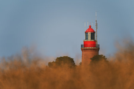 A red lighthouse and a field near it during the daytimeの写真素材