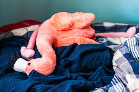 A fluffy pink flamingo toy on the bed in Poznan, Poland