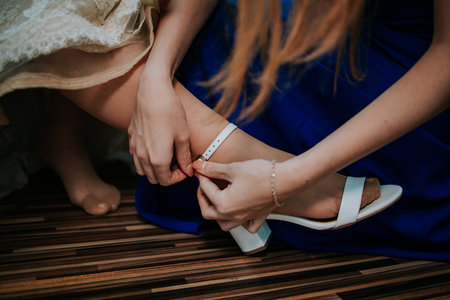 A closeup shot of female hands attaching the bride shoe buckle