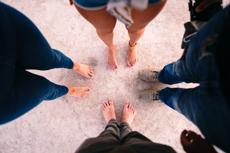A high angle shot of feet of four people standing on the groundの写真素材