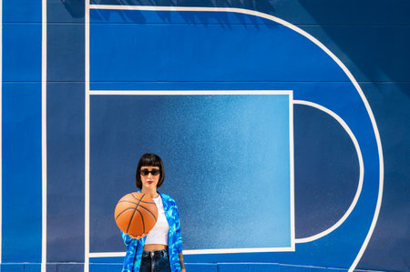 A Caucasian girl from Spain holding a basketball ball on blue backgroundの写真素材