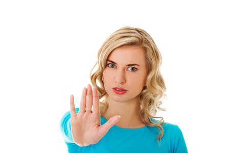 A blonde Polish woman in blue clothes showing a stop sign isolated on white background