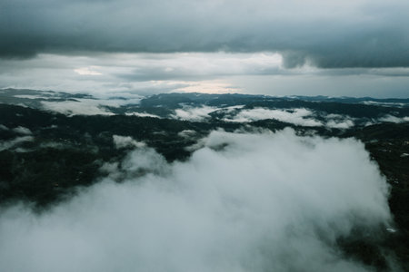 A mesmerizing view of mountains covered with clouds under a gloomy skyの写真素材