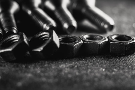 A grayscale shot of a pile of bolts and nuts on a grunge backgroundの写真素材