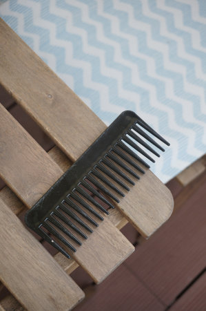 A closeup shot of a black comb on wooden backgroundの写真素材