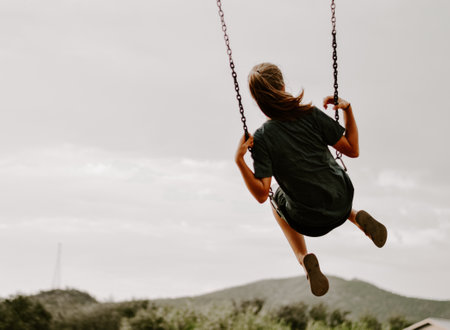 A back view of a female in the air on a swingの写真素材