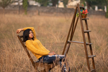 A portrait of a beautiful African female in a yellow sweater posing in a fieldの写真素材
