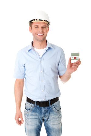 A young happy engineer in a helmet holding a small house modelの写真素材