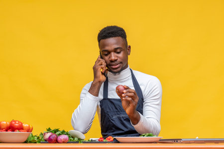 A closeup shot of an African male chef preparing food in front of a yellow wallの写真素材