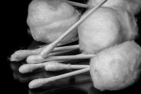A closeup shot of cotton pieces and Q-tips on the black surfaceの写真素材