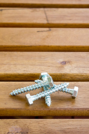 A vertical closeup shot of silver cross screws on a wooden tableの写真素材