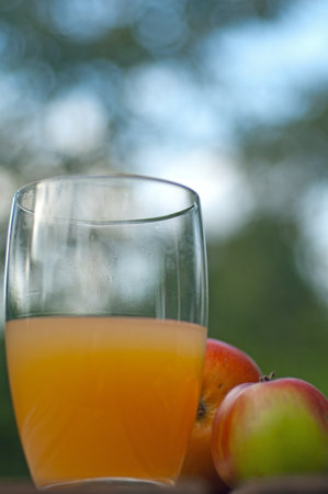 Natural cloudy freshly squeezed apple juice in drinking glass with two apples in portrait formatの写真素材