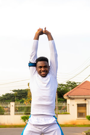 A vertical shot of an African male in a sporty outfit doing some stretchingの写真素材