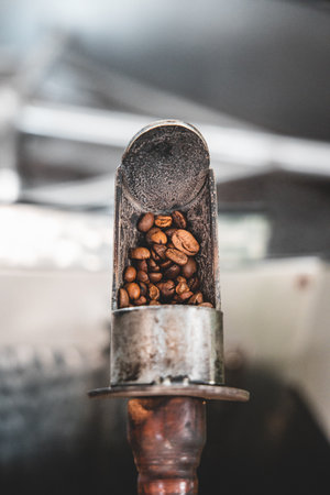A vertical shot of a small metal coffee roaster with coffee beansの写真素材