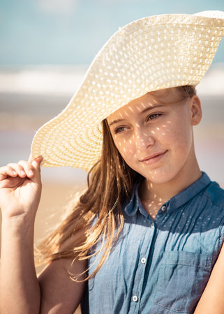 A vertical shot of a Caucasian, attractive young lady with a summer hat on the beach in Netherlandsの写真素材