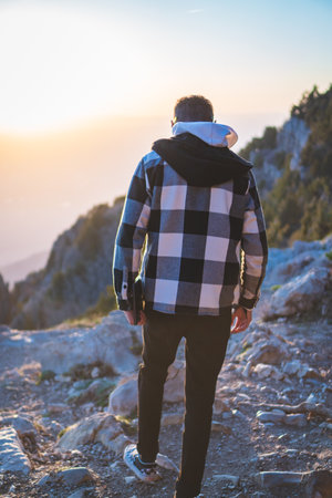 A young man walking on the rocky trail on a sunny morningの写真素材