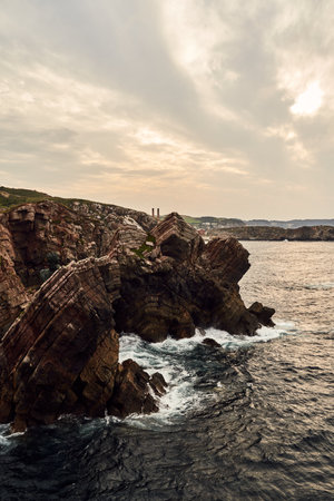 A vertical shot of an eye-catchy view of a  rocky coastline on a sunsetの写真素材