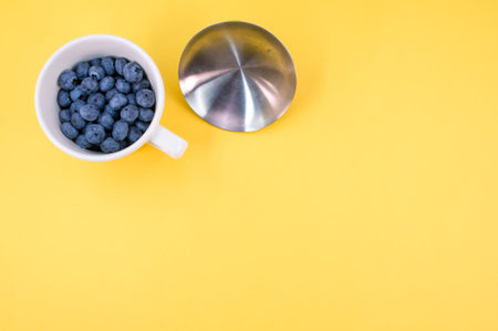 A top view of blueberries in a mug on a yellow backgroundの写真素材