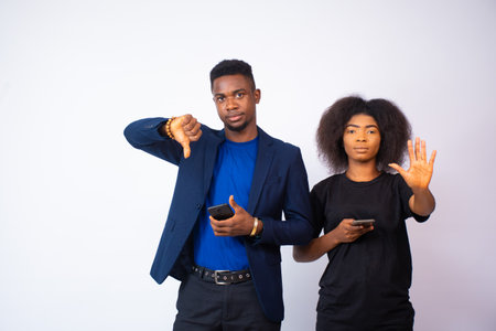 A young African couple doing a thumbs down and a stop symbol isolated on a white backgroundの写真素材