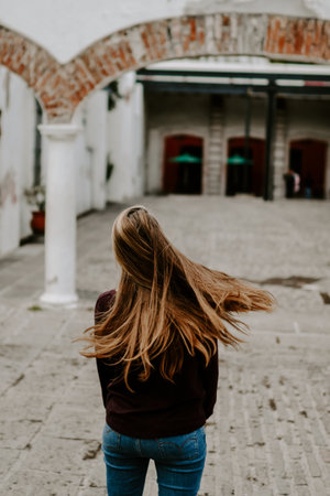 A vertical shot of a young female walking near ruins on a windy dayの写真素材