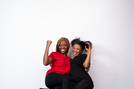 A pair of young African female friends happily posing isolated on a white backgroundの写真素材